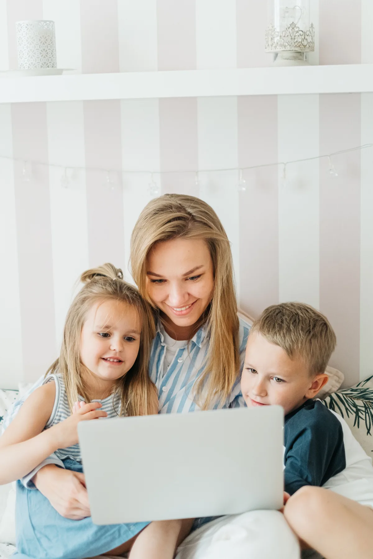 A mother and her two children looking at a laptop together