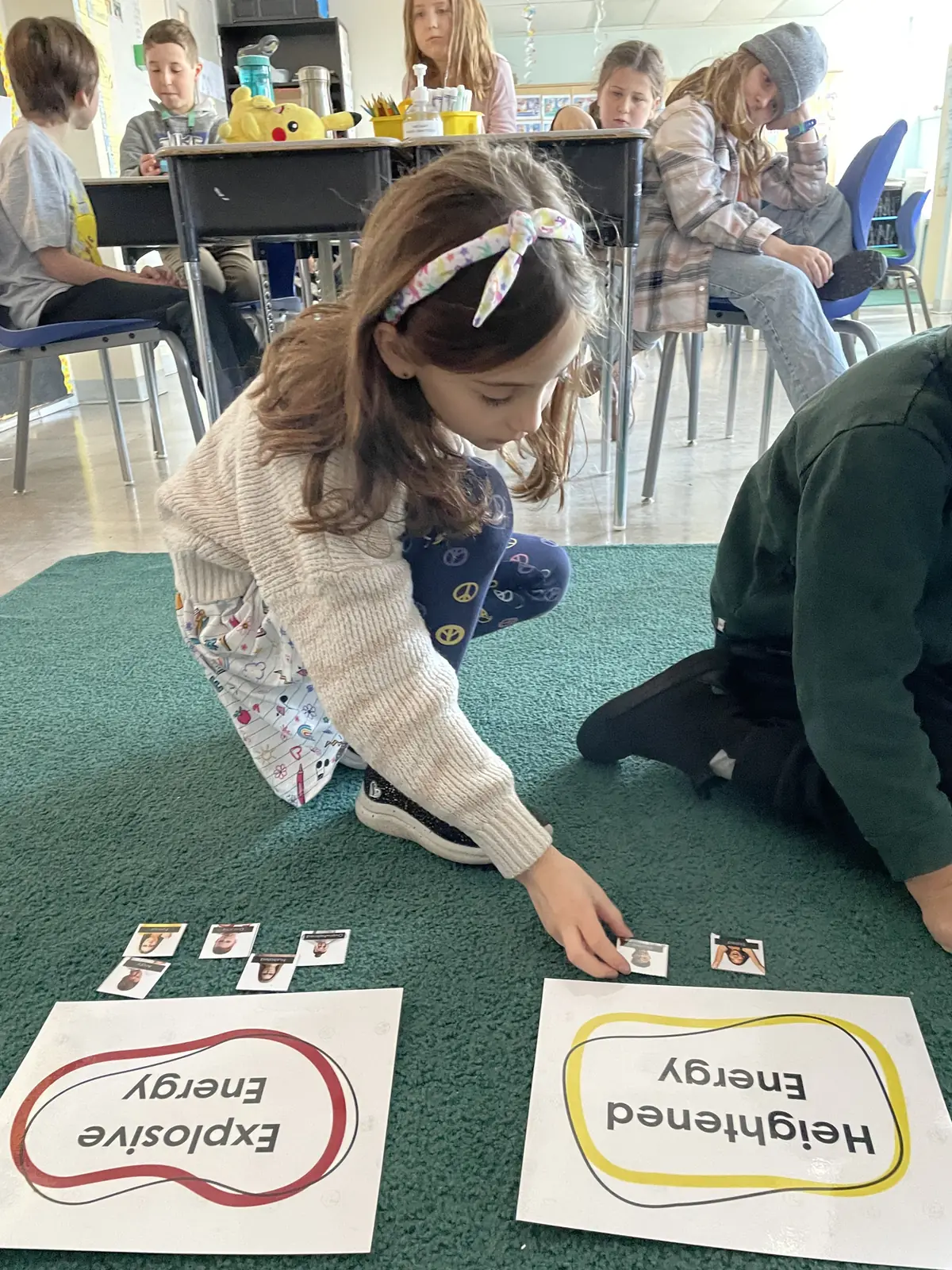 Student sorting emotion cards on the classroom floor